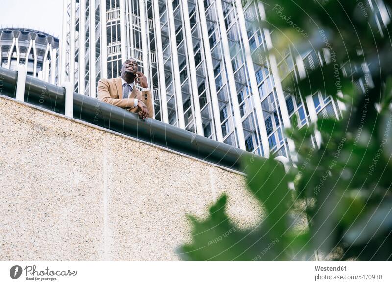 Young businessman leaning on a railing in the city talking on the phone business life business world business person businesspeople Business man Business men