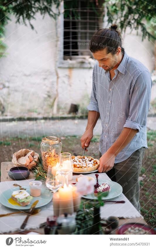 Man arranging a romantic candlelight meal outdoors men males candle light lyrical Romance Meals Adults grown-ups grownups adult people persons human being