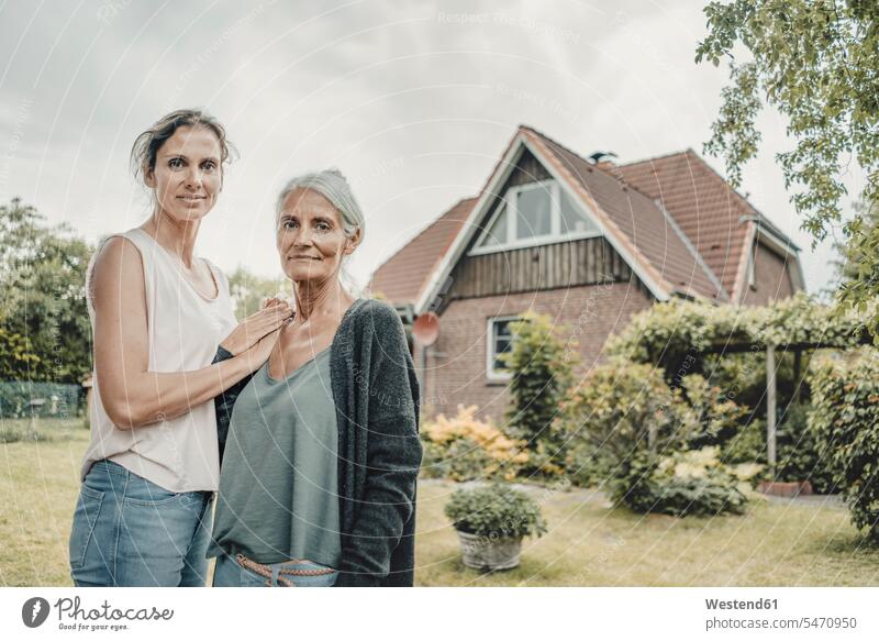 Mother and daughter standing in garden, inf ront of their house human human being human beings humans person persons caucasian appearance caucasian ethnicity