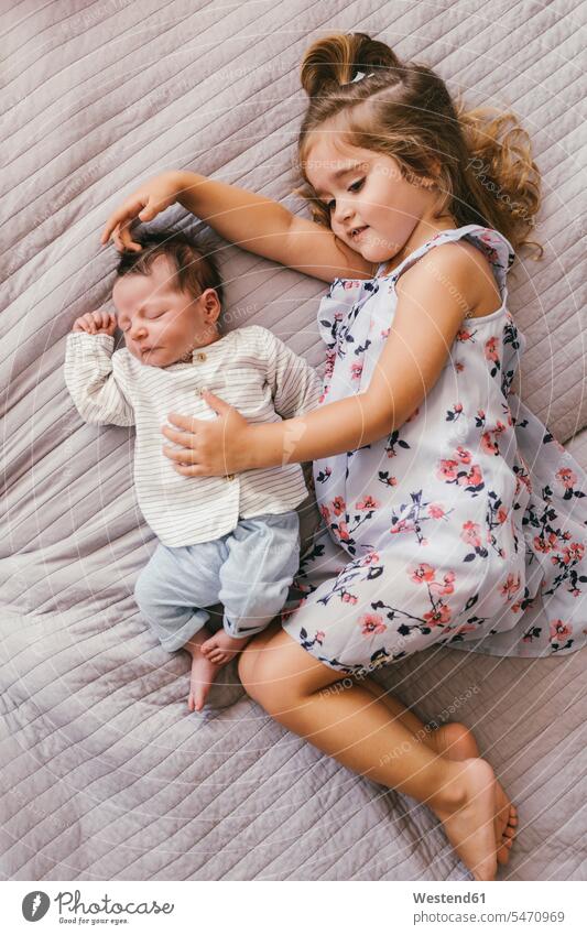 Girl lying on blanket cuddling with her baby brother laying down lie lying down smiling smile infants nurselings babies snuggle cuddle snuggling Blanket