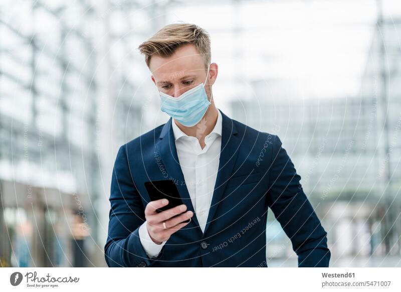 Businessman using smart phone while wearing face mask in city color image colour image outdoors location shots outdoor shot outdoor shots day daylight shot