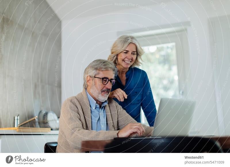 Mature man with wife using laptop on kitchen table at home human human being human beings humans person persons caucasian appearance caucasian ethnicity
