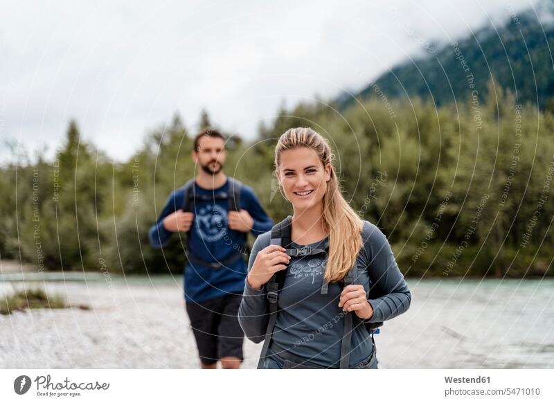 Young couple on a hiking trip at riverside, Vorderriss, Bavaria, Germany touristic tourists back-pack back-packs backpacks rucksack rucksacks go going walk