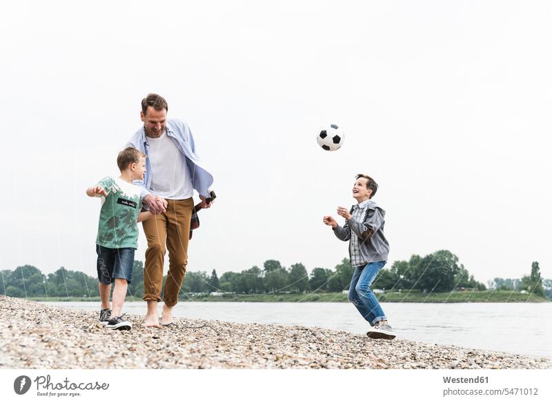 Happy father with two sons and football walking at the riverside soccer ball soccer balls footballs manchild manchildren pa fathers daddy dads papa going