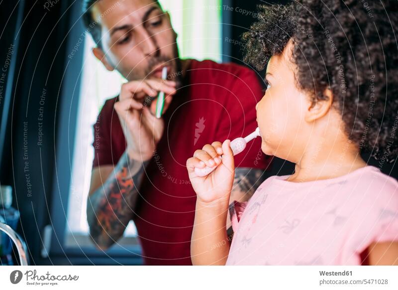 Close-up of baby girl with father brushing teeth in bathroom at home color image colour image casual clothing casual wear leisure wear casual clothes