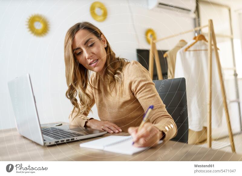 Businesswoman working while sitting by table at home color image colour image indoors indoor shot indoor shots interior interior view Interiors day