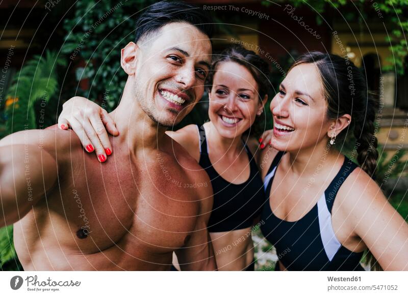 Shirtless man standing with female friends in yard color image colour image Spain outdoors location shots outdoor shot outdoor shots day daylight shot