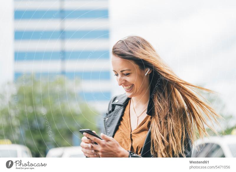 Happy young woman with windswept hair using cell phone in the city mobile phone mobiles mobile phones Cellphone cell phones blowing happiness happy town cities