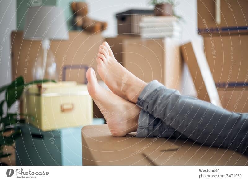Bare feet of woman relaxing surrounded by cardboard boxes in a new home human human being human beings humans person persons caucasian appearance