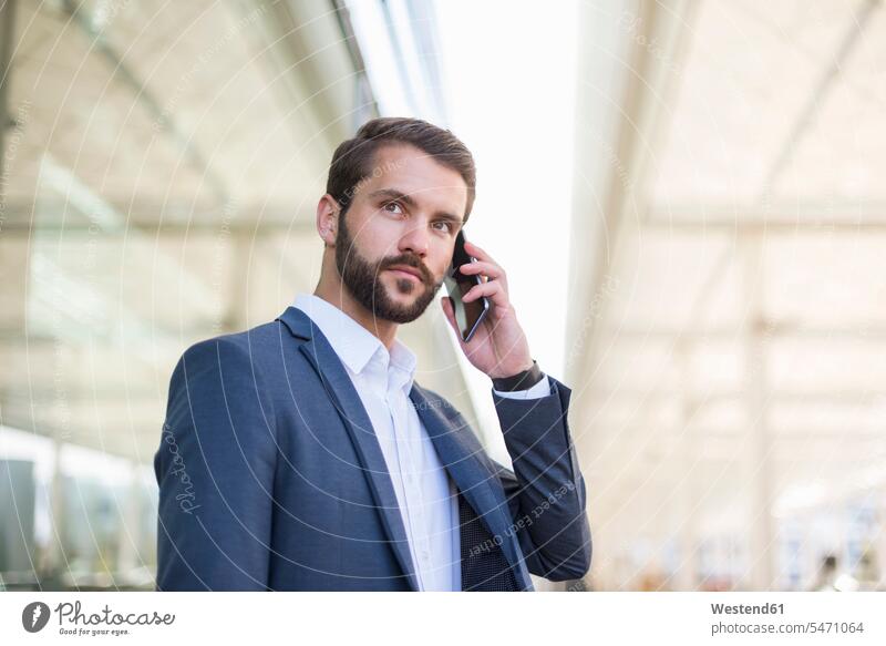 Young businessman on cell phone looking sideways Businessman Business man Businessmen Business men on the phone call telephoning On The Telephone calling