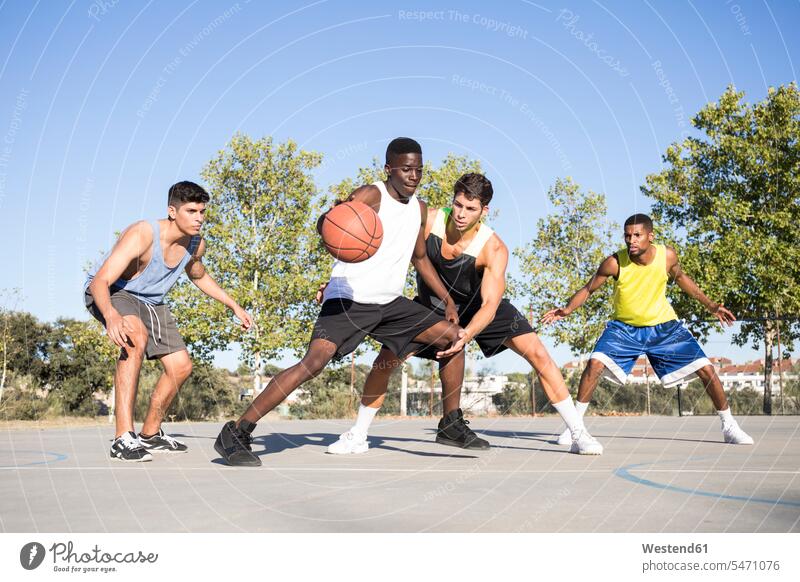 Young men playing basketball and dribbling ball on sports ground Sports Team Sports Teams teams balls exercise practising train training free time leisure time
