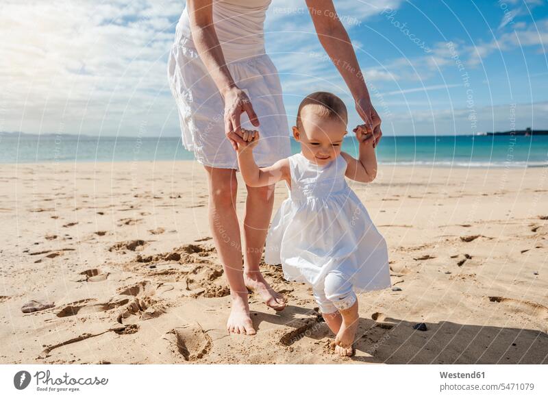 Mother helping little daughter walking on the beach assistance assisting Help mother mommy mothers ma mummy mama daughters baby infants nurselings babies