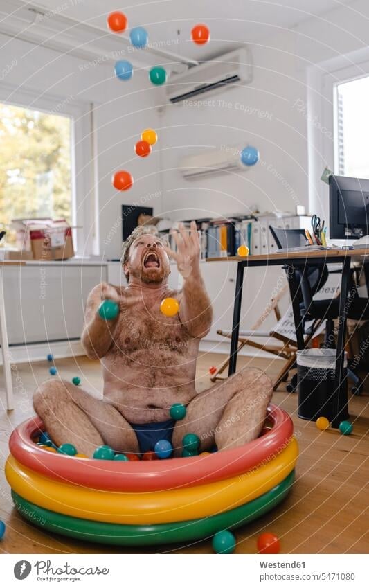 Crazy businessman sitting in wading pool in office playing with balls Occupation Work job jobs profession professional occupation business life business world