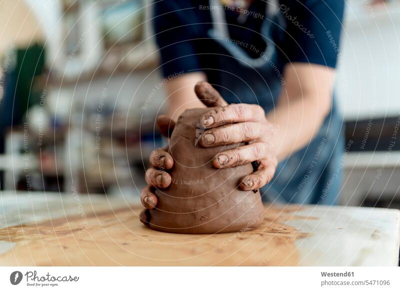 Female artist molding a shape from brown clay in crafts workshop color image colour image indoors indoor shot indoor shots interior interior view Interiors