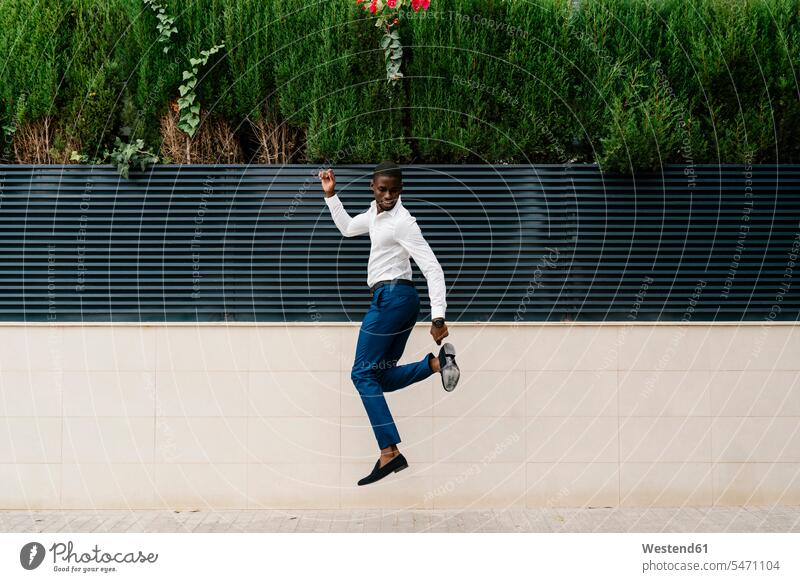 Male professional jumping on sidewalk against surrounding wall in city color image colour image Spain outdoors location shots outdoor shot outdoor shots day