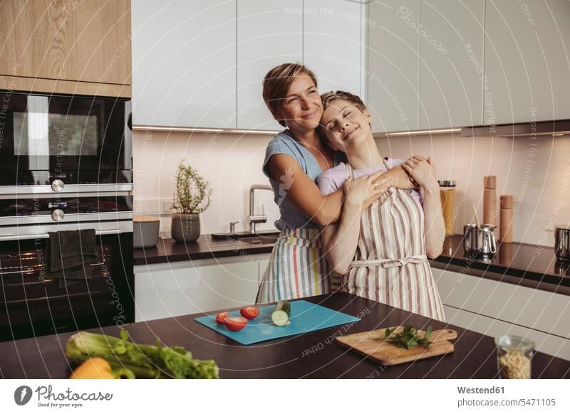 Happy lesbian couple standing in kitchen with aprons twosomes partnership couples happiness happy people persons human being humans human beings eyes closed