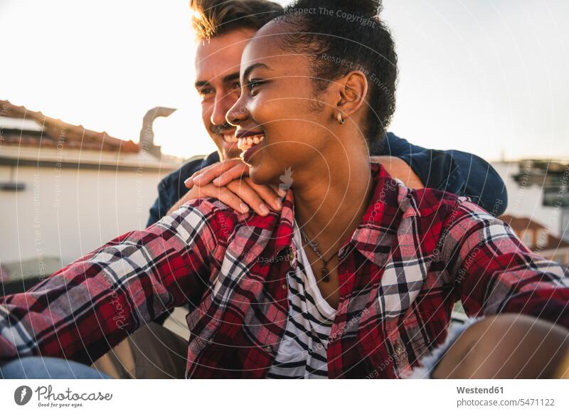 Happy affectionate young couple sitting on rooftop in the evening human human being human beings humans person persons African black black ethnicity coloured