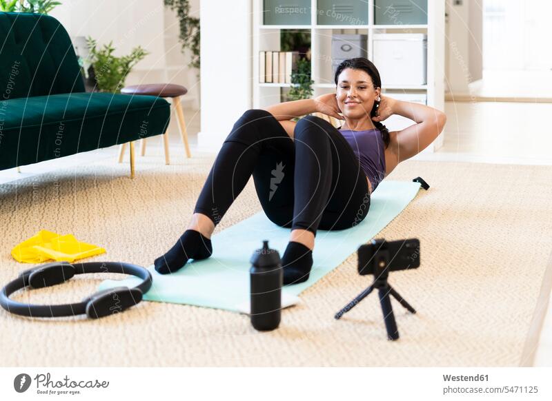 Young woman doing crunches with hands behind head while lying down at home color image colour image indoors indoor shot indoor shots interior interior view
