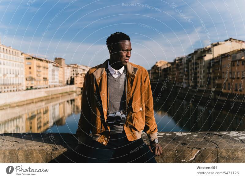 Young man with a camera on a bridge above river Arno, Florence, Italy human human being human beings humans person persons African black black ethnicity