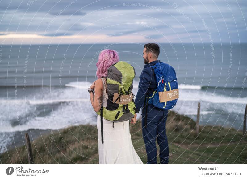 Bridal couple on viewpoint and ocean in the background back-pack back-packs backpacks rucksack rucksacks in the evening Late Evening delight enjoyment Pleasant