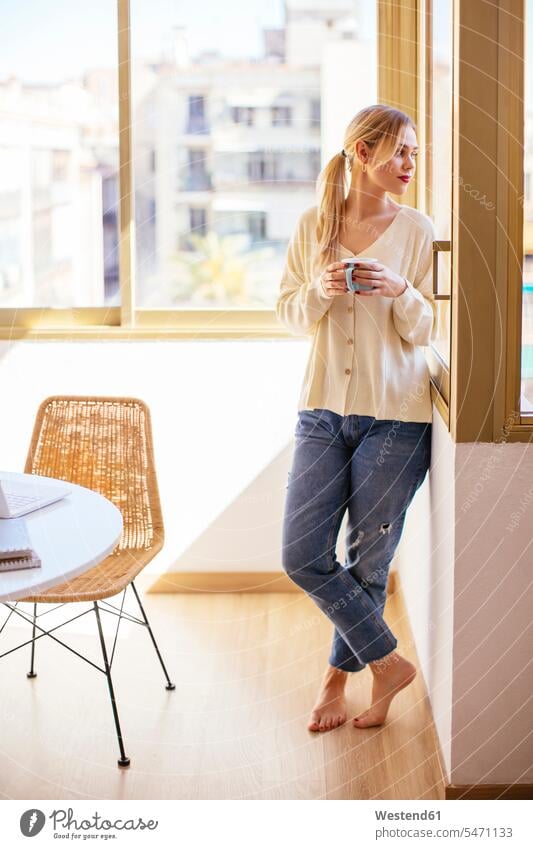 Blonde woman with cup of coffee looking out of the window females women blond blond hair blonde hair Looking Through Window Looking Through A Window