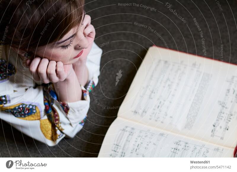 Female student reading a music book in a public library books musician female musician musicians female students woman females women lying laying down lie