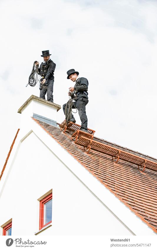 Two chimney sweeps working on house roof caucasian caucasian ethnicity caucasian appearance european colleagues day daylight shot daylight shots day shots