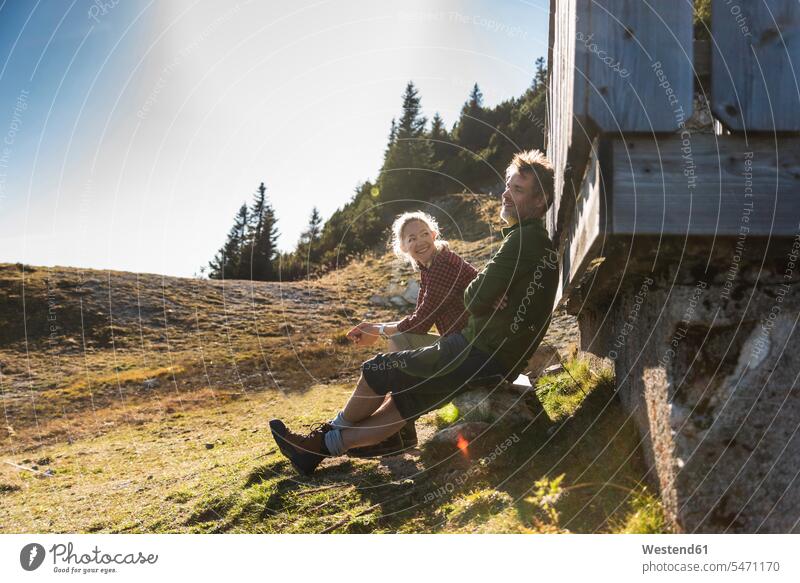 Hiking couple sitting in front of mountain hut, taking a break mountaineering mountain range mountains mountain ranges Seated resting twosomes partnership