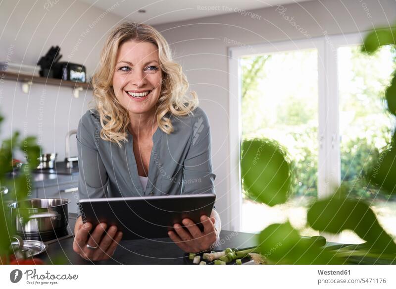 Smiling woman using tablet in kitchen females women domestic kitchen kitchens digitizer Tablet Computer Tablet PC Tablet Computers iPad Digital Tablet