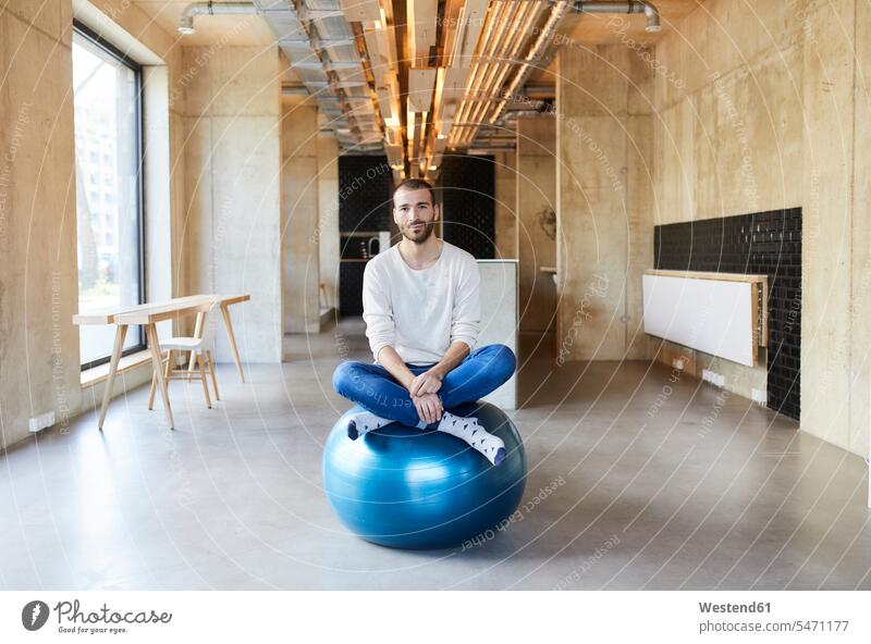 Portrait of young man sitting on fitness ball in modern office caucasian caucasian ethnicity caucasian appearance european posture position body posture offices