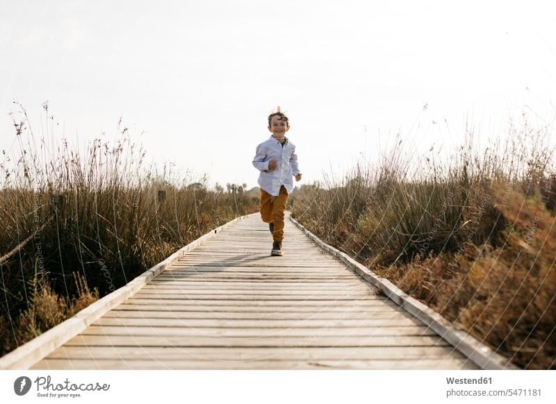 Happy little boy running on boardwalk caucasian caucasian ethnicity caucasian appearance european front view frontal View From Front Frontal View front views
