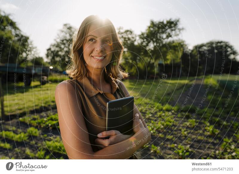 Smiling young woman holding tablet on a farm in the countryside business life business world business person businesspeople business woman business women