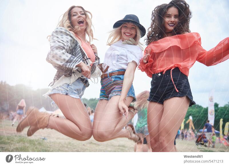 Happy friends jumping during music festival female friends exuberance hilarity Frolic exuberant jump in the air jumping in the air Leaping woman females women