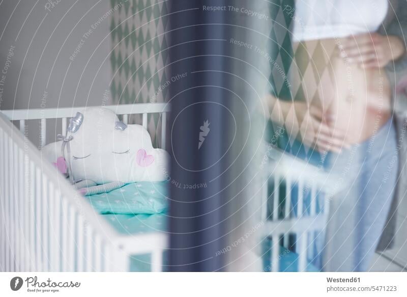 Mirrored pregnant woman, baby bed in the background stroking petting belly bellies abdomen human abdomen holding baby cot baby crib females women baby belly