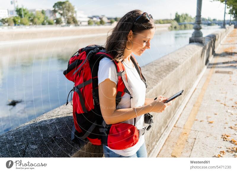 Young female backpacker using smartphone at a river in Verona, Italy human human being human beings humans person persons caucasian appearance