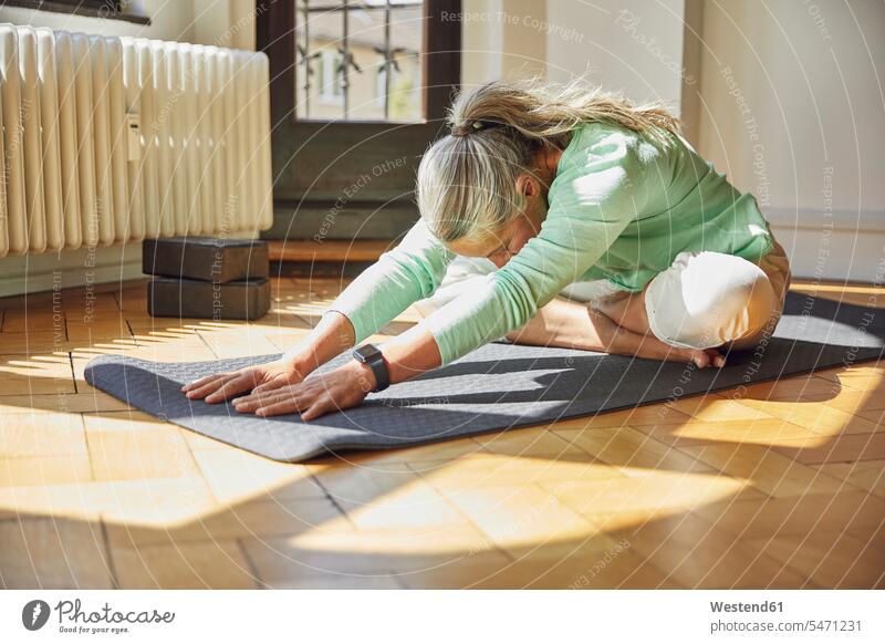 Woman exercising on exercise mat over floor in living room Germany indoors indoor shot indoor shots interior interior view Interiors day daylight shot