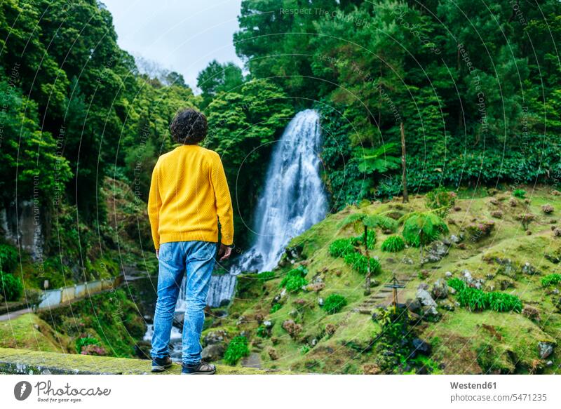 Azores, Sao Miguel, rear view of man looking at a waterfall in the Ribeira dos Caldeiroes Natural Park standing men males seeing viewing Adults grown-ups