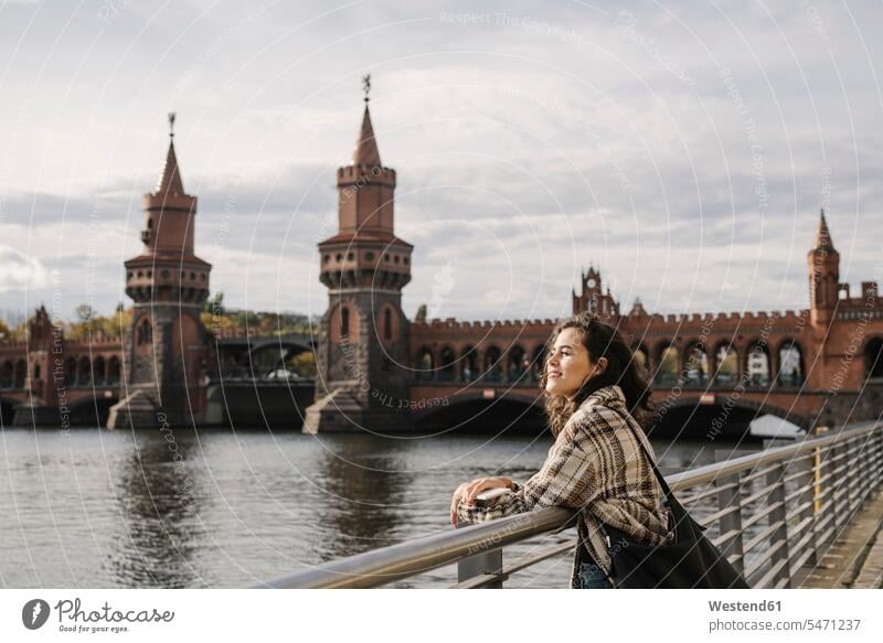 Smiling woman with smartphone in the city at Oberbaum Bridge, Berlin, Germany bags telecommunication phones telephone telephones cell phone cell phones