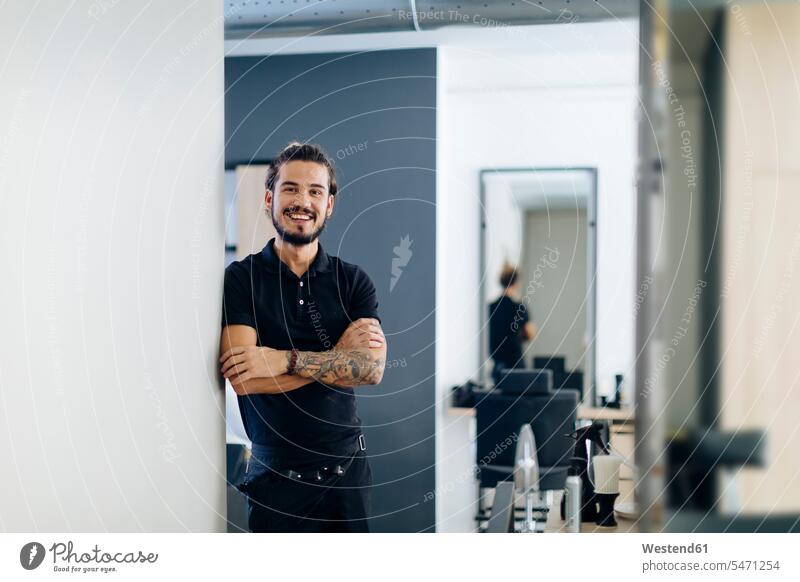 Confident male barber standing arms crossed in hair salon color image colour image indoors indoor shot indoor shots interior interior view Interiors day