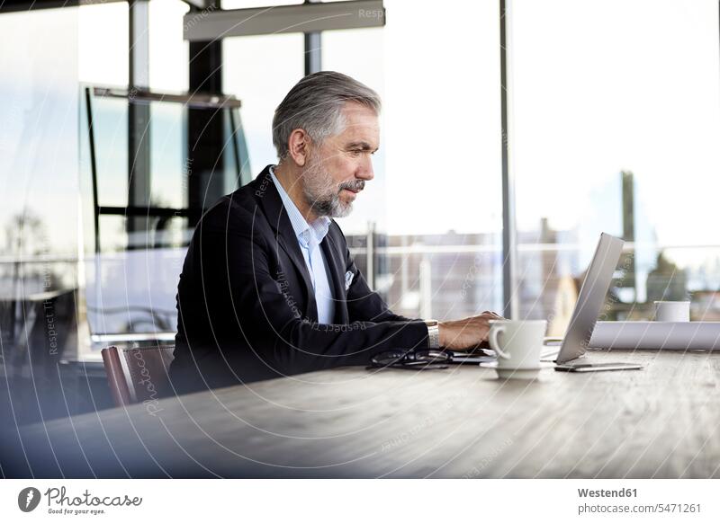 Businessman using laptop at desk in office Business man Businessmen Business men Laptop Computers laptops notebook offices office room office rooms desks