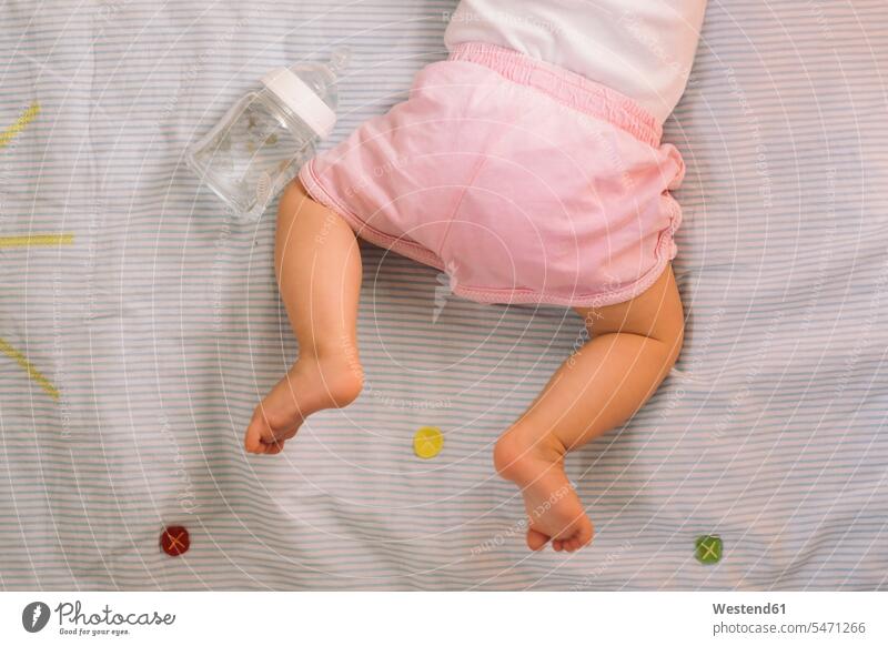 Barefoot baby girl wearing pink knickers lying on bedspread, partial view barefoot naked feet naked foot Barefeet Bare Feet Bare Foot Barefooted bare-footed