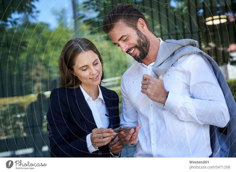Businessman and businesswoman looking at cell phone in the city business life business world business person businesspeople associate associates