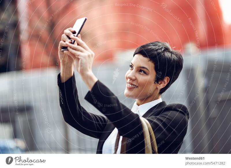 Portrait of smiling young businesswoman taking selfie with cell phone Selfie Selfies smile portrait portraits Smartphone iPhone Smartphones females women