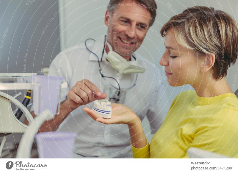 Dentist explaining dental bridg on a tooth model to his patient treatment Medical Treatment treatments dentist dental surgeon healthcare and medicine medical