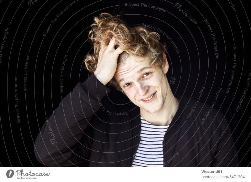 Portrait of smiling young man with hand in hair against black background human human being human beings humans person persons caucasian appearance