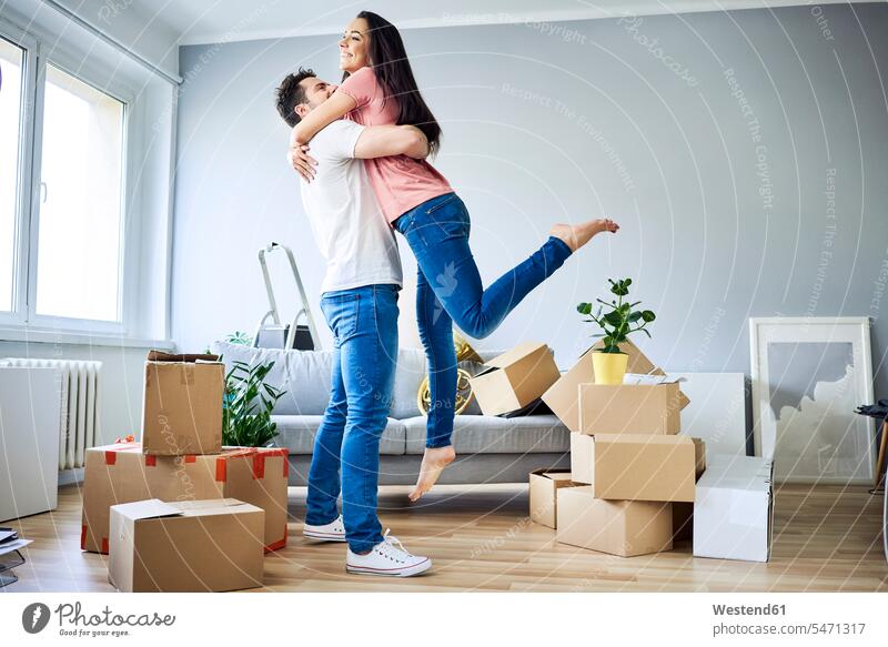 Happy couple celebrating moving in together cardboard box cardboard boxes packing case packing cases cheerful gaiety Joyous glad Cheerfulness exhilaration merry