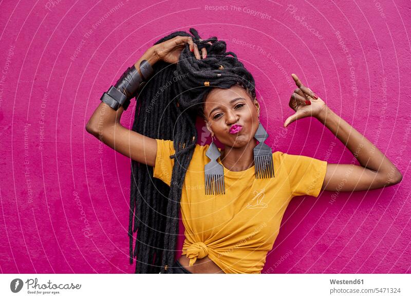 Portrait of woman with long dreadlocks making shaka sign in front of a pink wall T- Shirt t-shirts tee-shirt hold cheer exultation jubilate jubilating rejoice