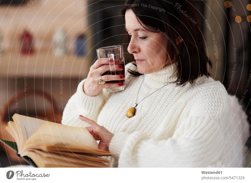 Mature woman with a hot drink reading a book females women Hot Drink Hot Drinks relaxed relaxation books Adults grown-ups grownups adult people persons