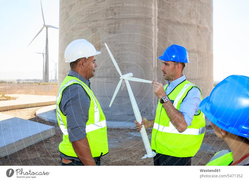 Three engineers with wind turbine model discussing on a wind farm wind park models discussion wind turbines wind power plant wind energy renewable energy