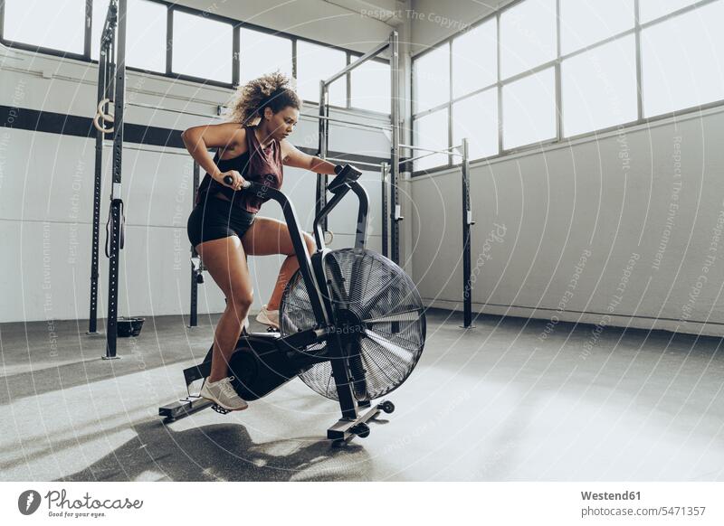 Young woman doing air bike workout in gym human human being human beings humans person persons Mixed Race mixed race ethnicity mixed-race Person 1